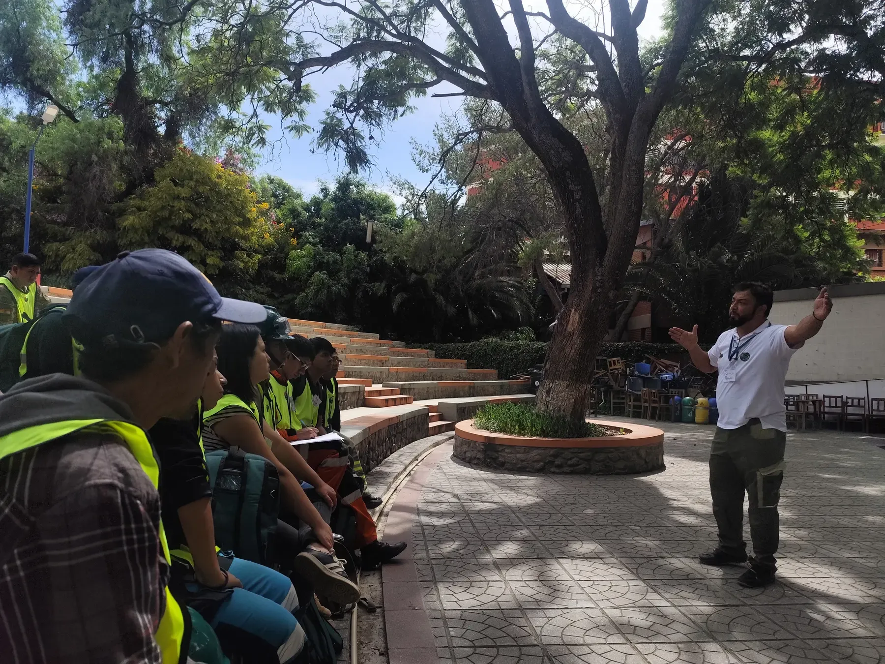Instructor con brazos abiertos capacita a voluntarios con chalecos amarillos en el anfiteatro al aire libre
